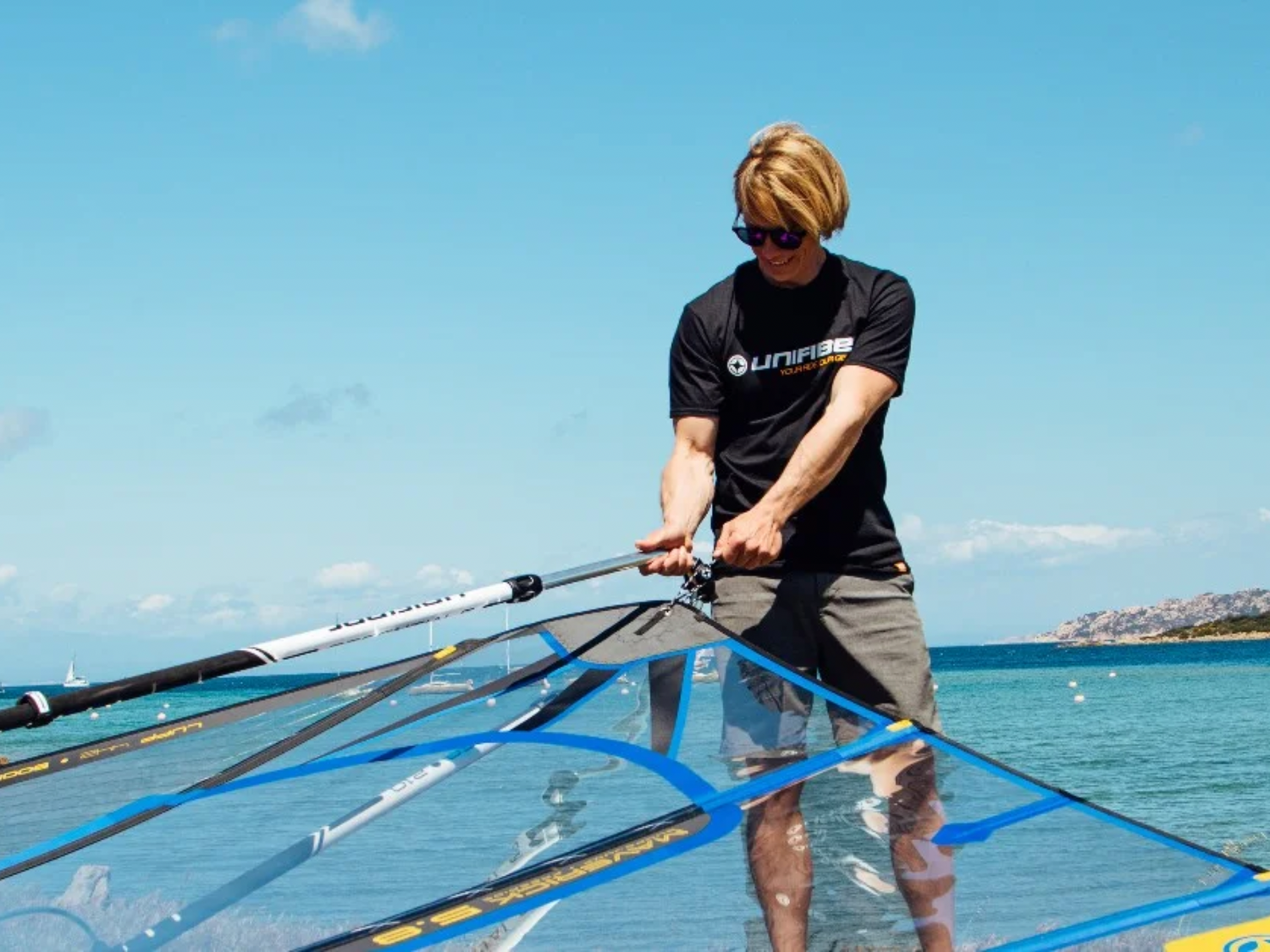Experienced windsurfer examining Unifiber Aluminium Boom on shoreline
