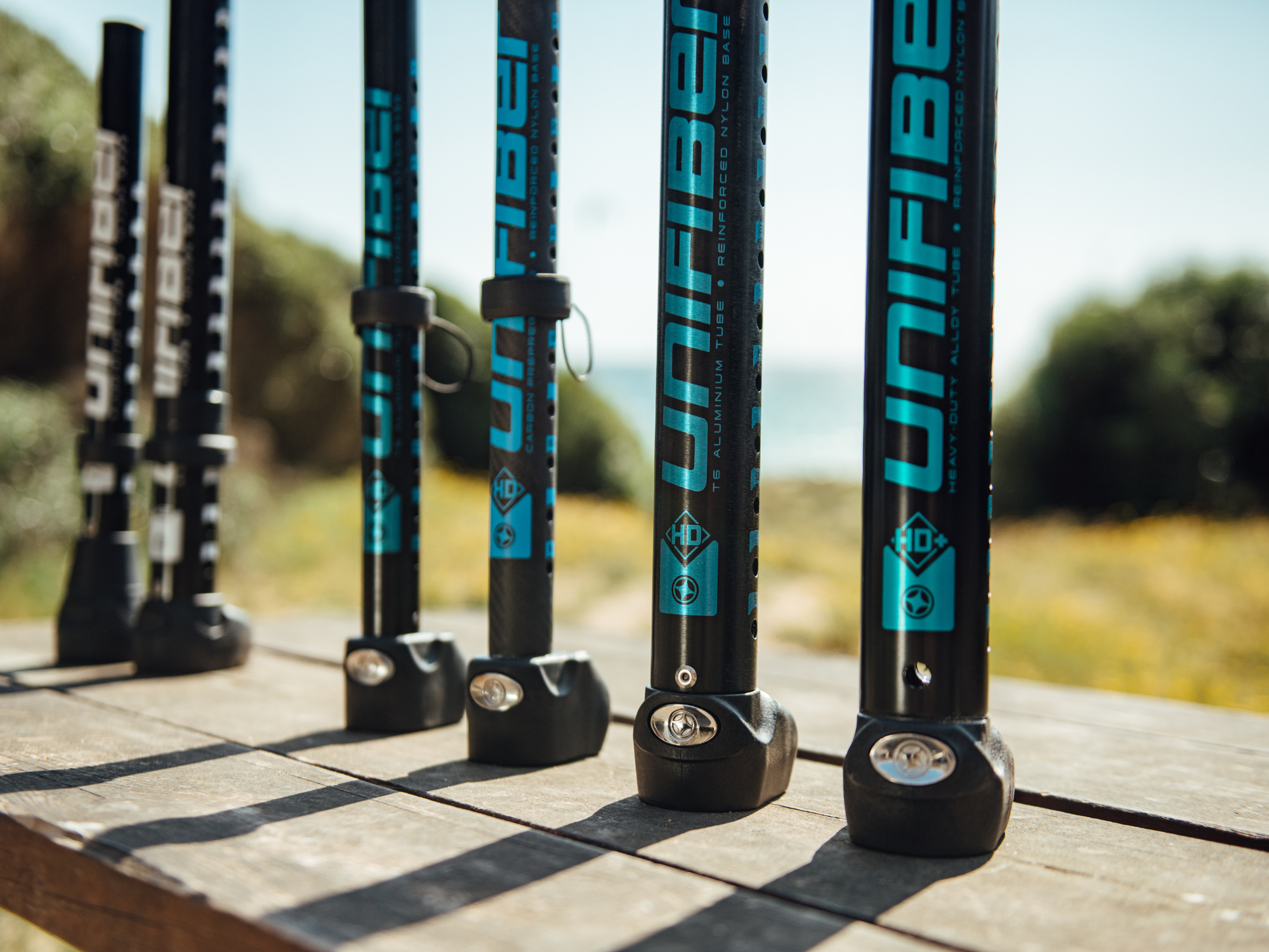 Unifiber mast materials comparison: Row of carbon and aluminum Unifiber masts standing upright, showcasing construction types.