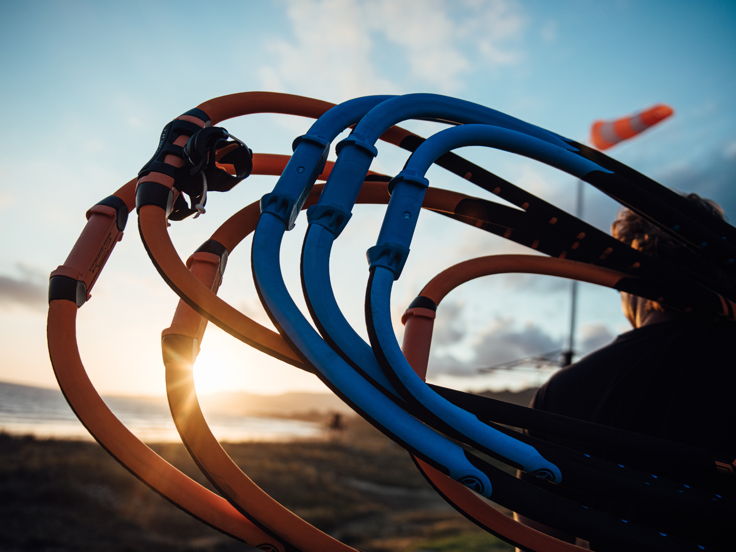 Multiple windsurf booms held by a person outside