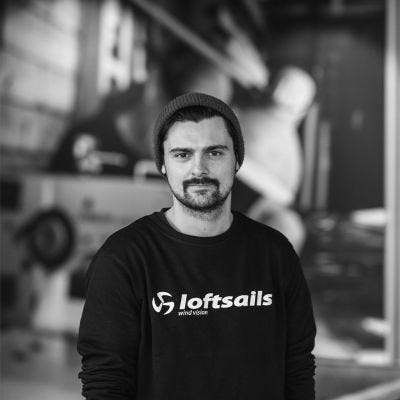 Someone wearing a tshirt with loftsails logo in a windsurf warehouse is wearing a loftsails logo.