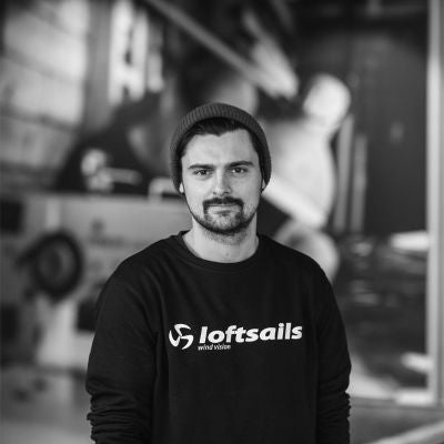 Someone wearing a tshirt with loftsails logo in a windsurf warehouse is wearing a loftsails logo.