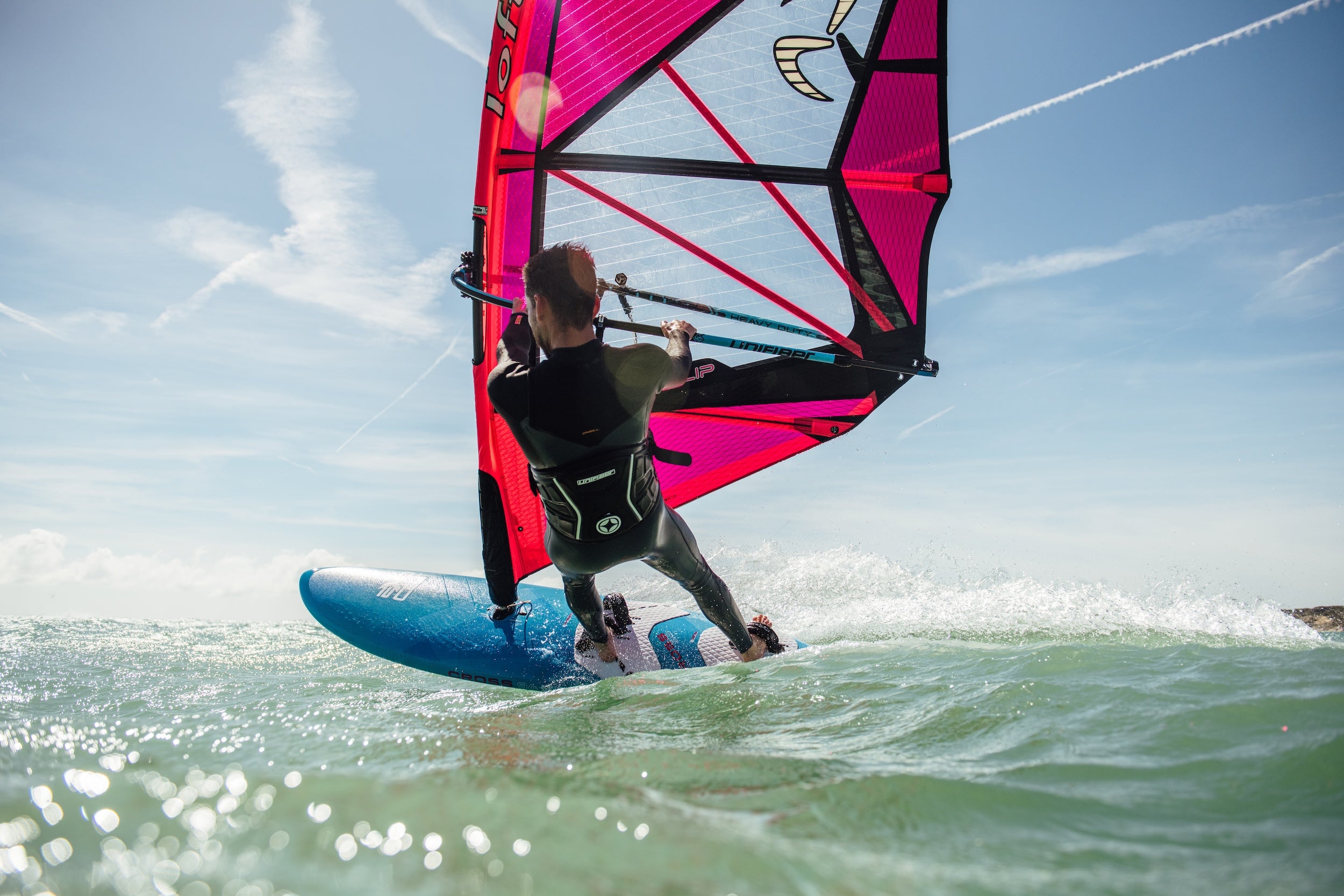 High-performance windsurf harness with pink sail, demonstrating optimal fit and support during wave riding