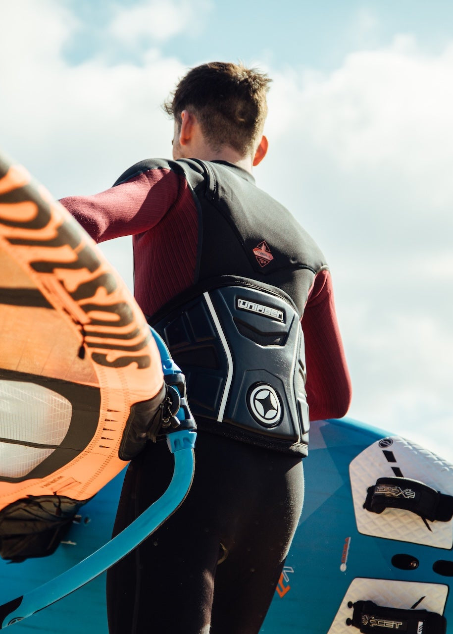Close-up shot of a windsurfer wearing a black and white wetsuit with visible winfsdurf harness from Unifiber