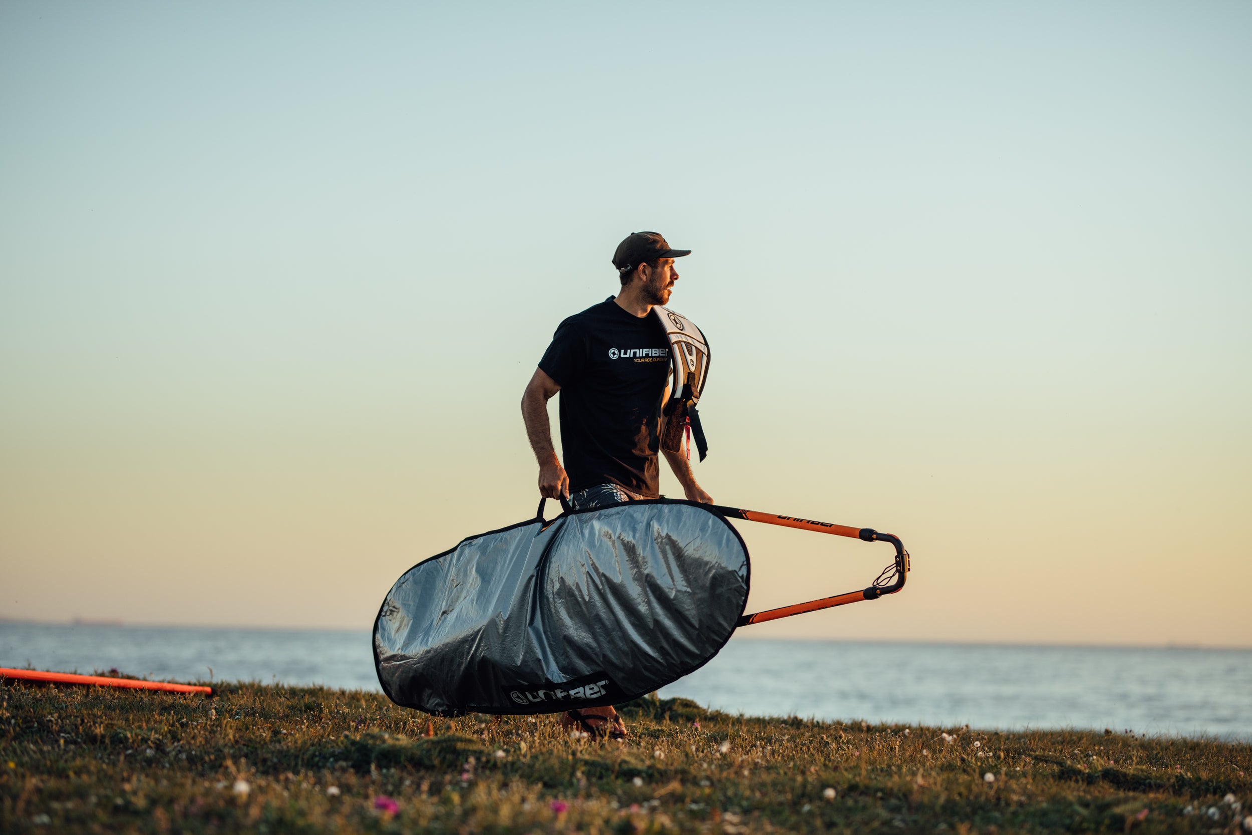 a windsurfer holidng a bag on beach