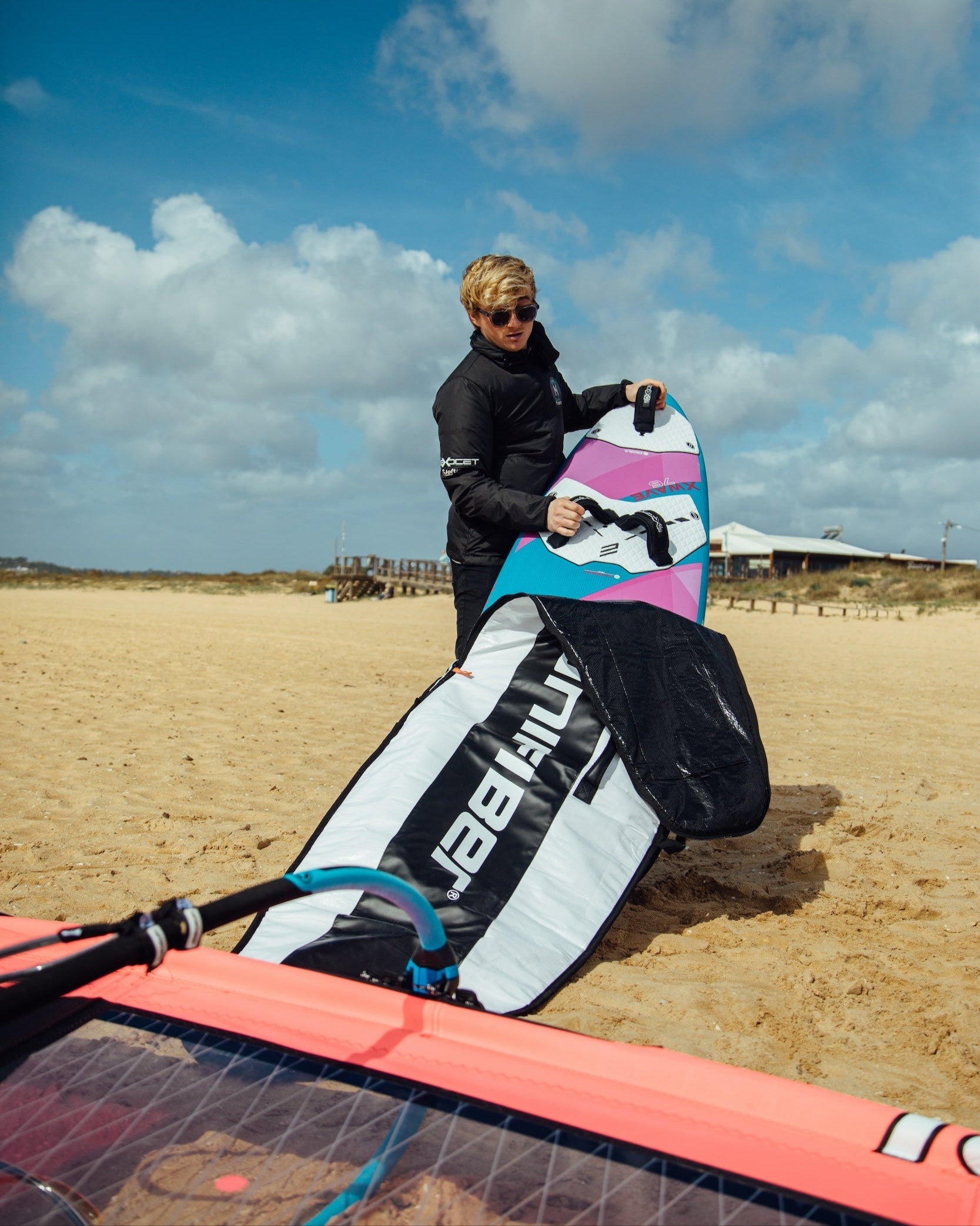 A windsurf board bag being packed on the beach