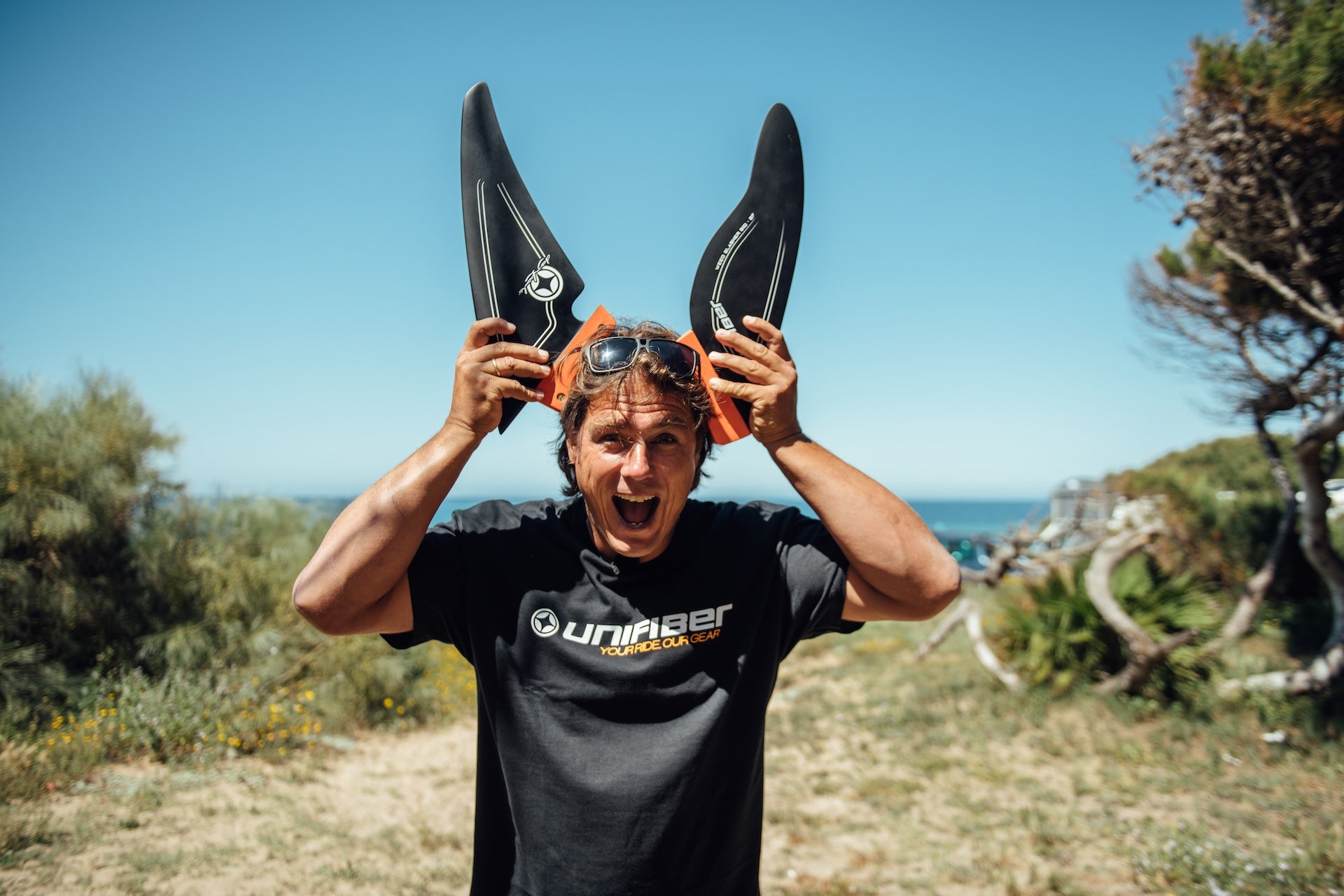 windsurfer holding two shallow water windsurfing fins made from G10