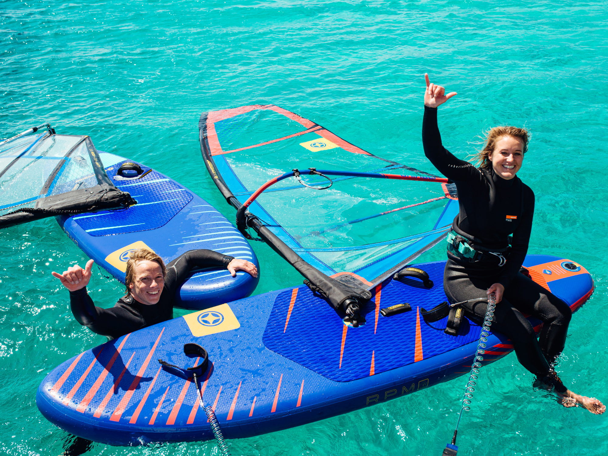 2 windsurfers on the water on inflatable windsurf boards