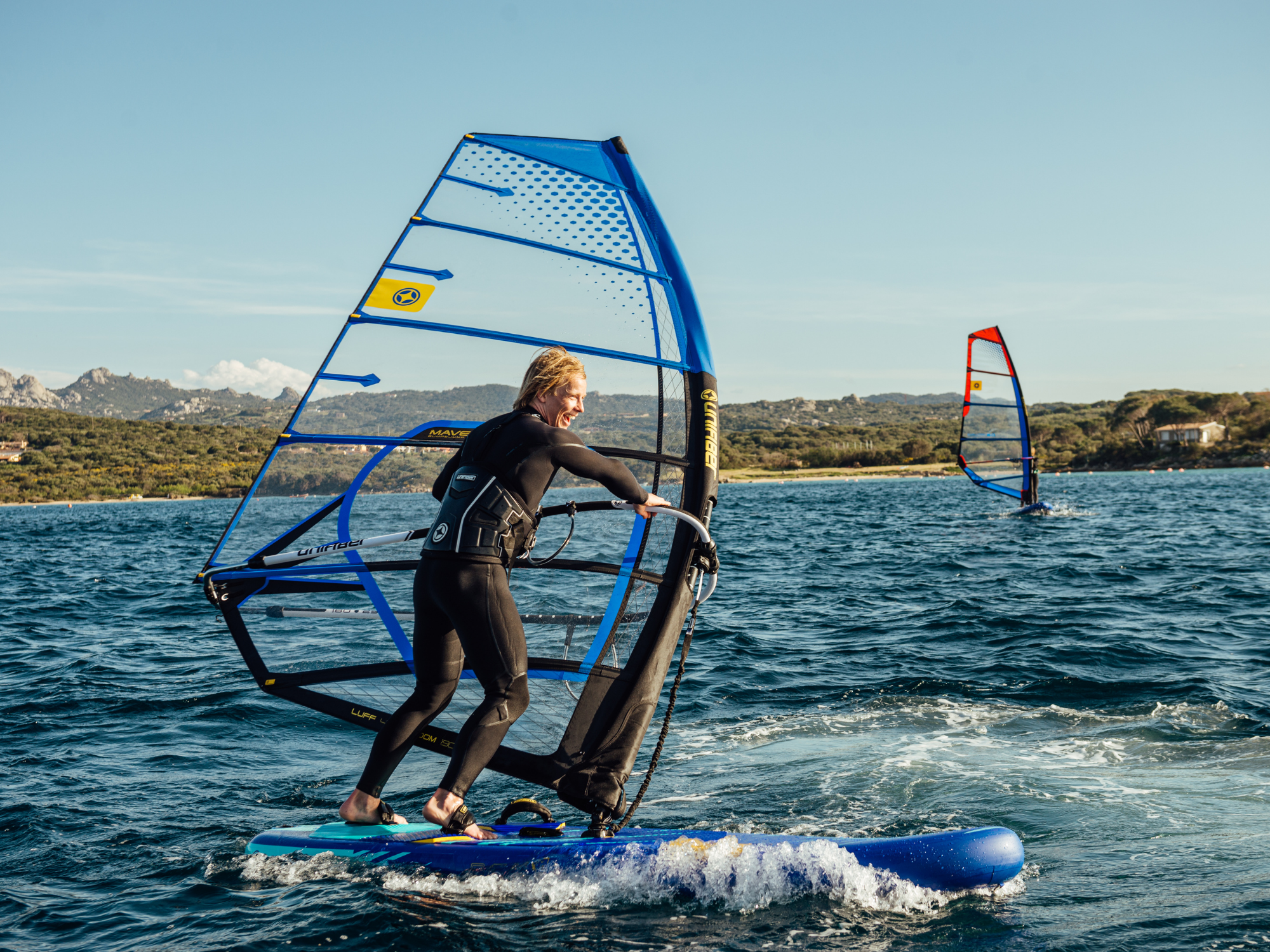 Unifiber Skywatch anemometer in action: Windsurfer navigates blue waters using precise wind measurement tech for optimal sail selection. 