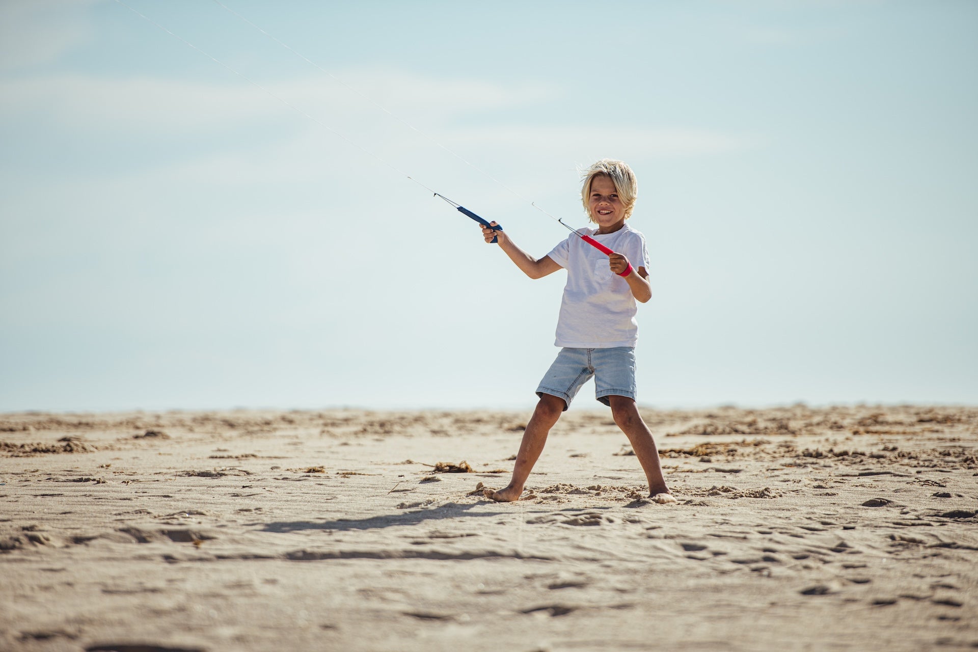 kid playing on the beach with a 2 line kite