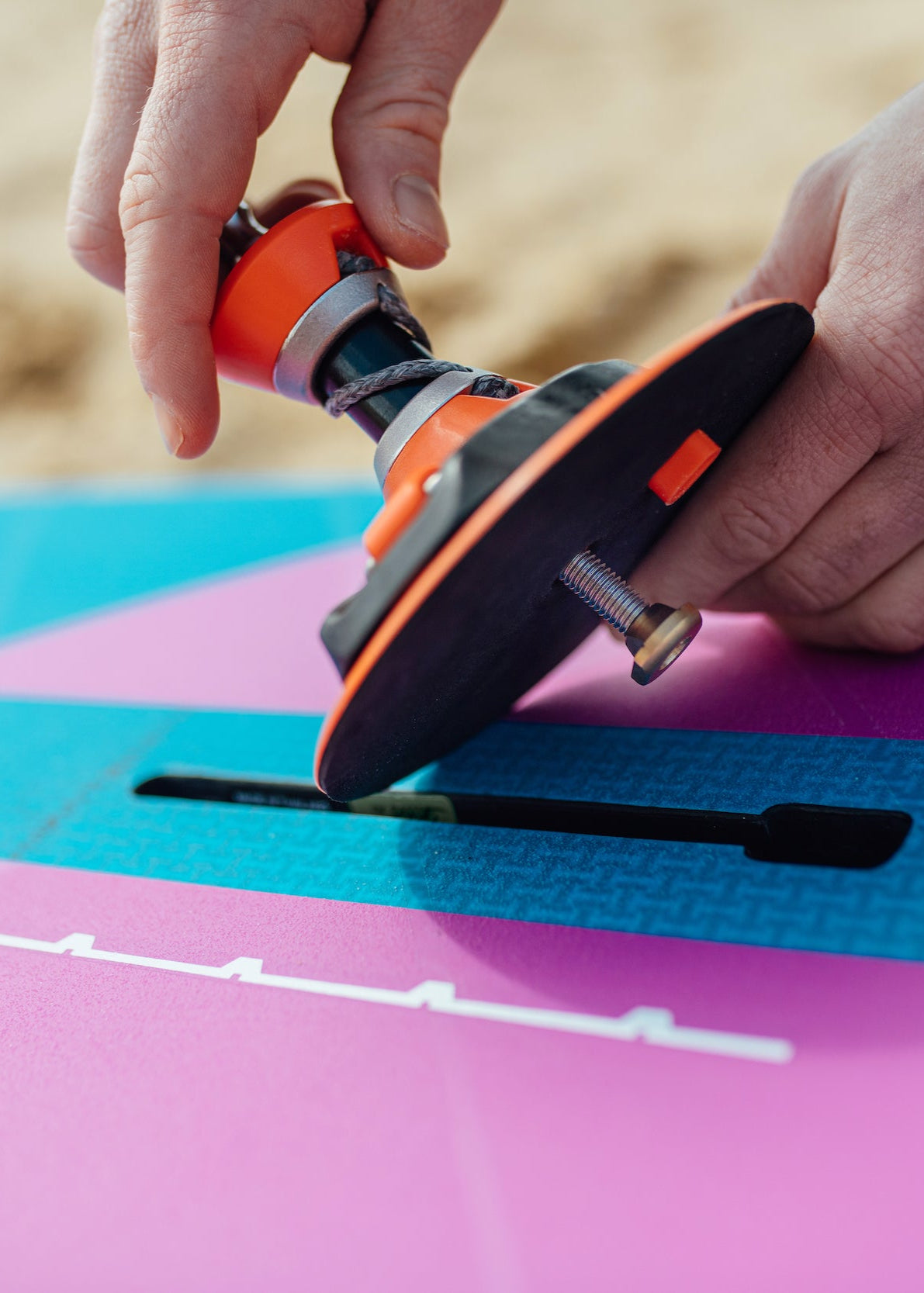 A rider putting his windsurf baseplate on the mast track of a windsurf wave board with a carbon integral construction 