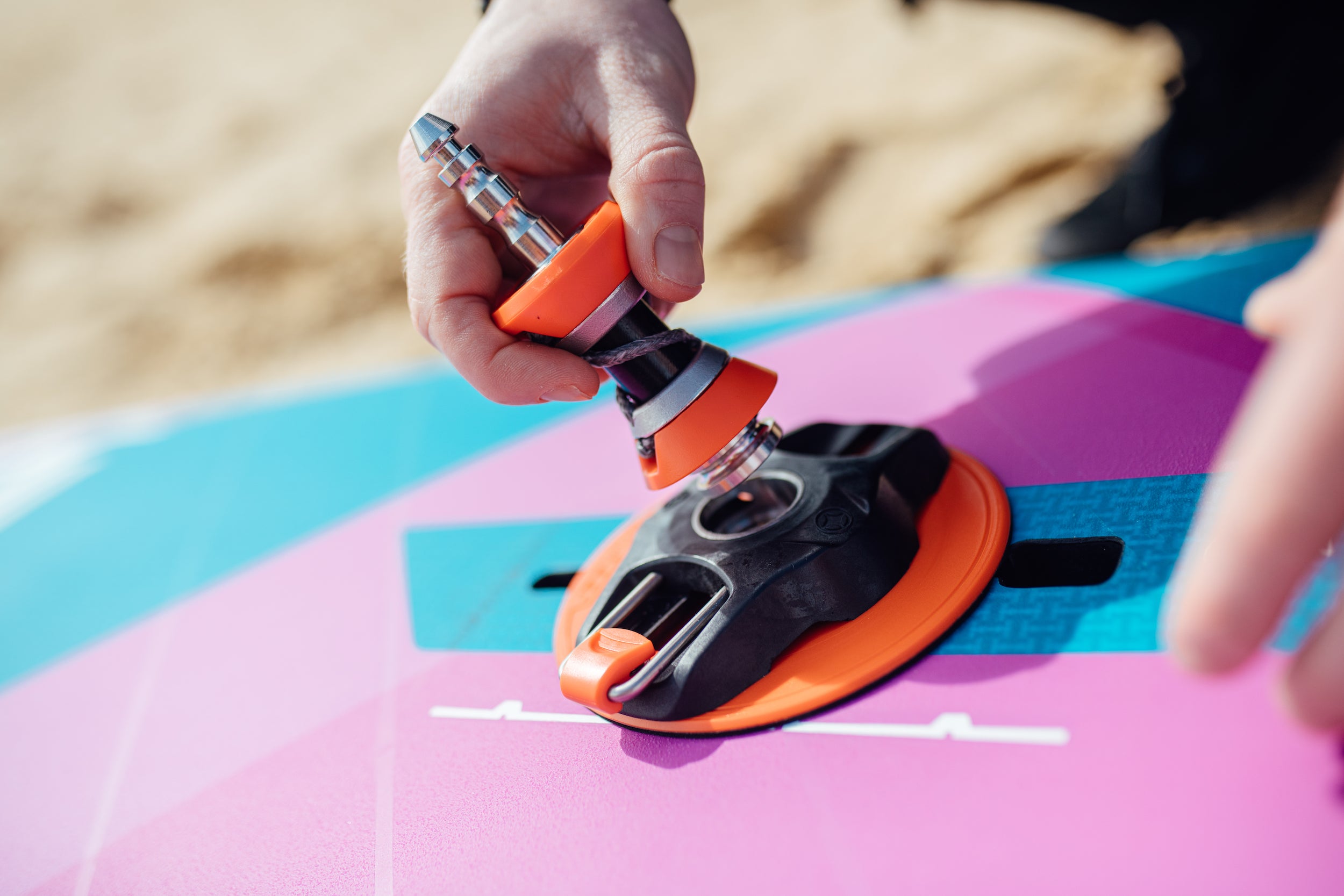 A rider putting his windsurf baseplate on the mast track of a windsurf wave board with a carbon integral construction 