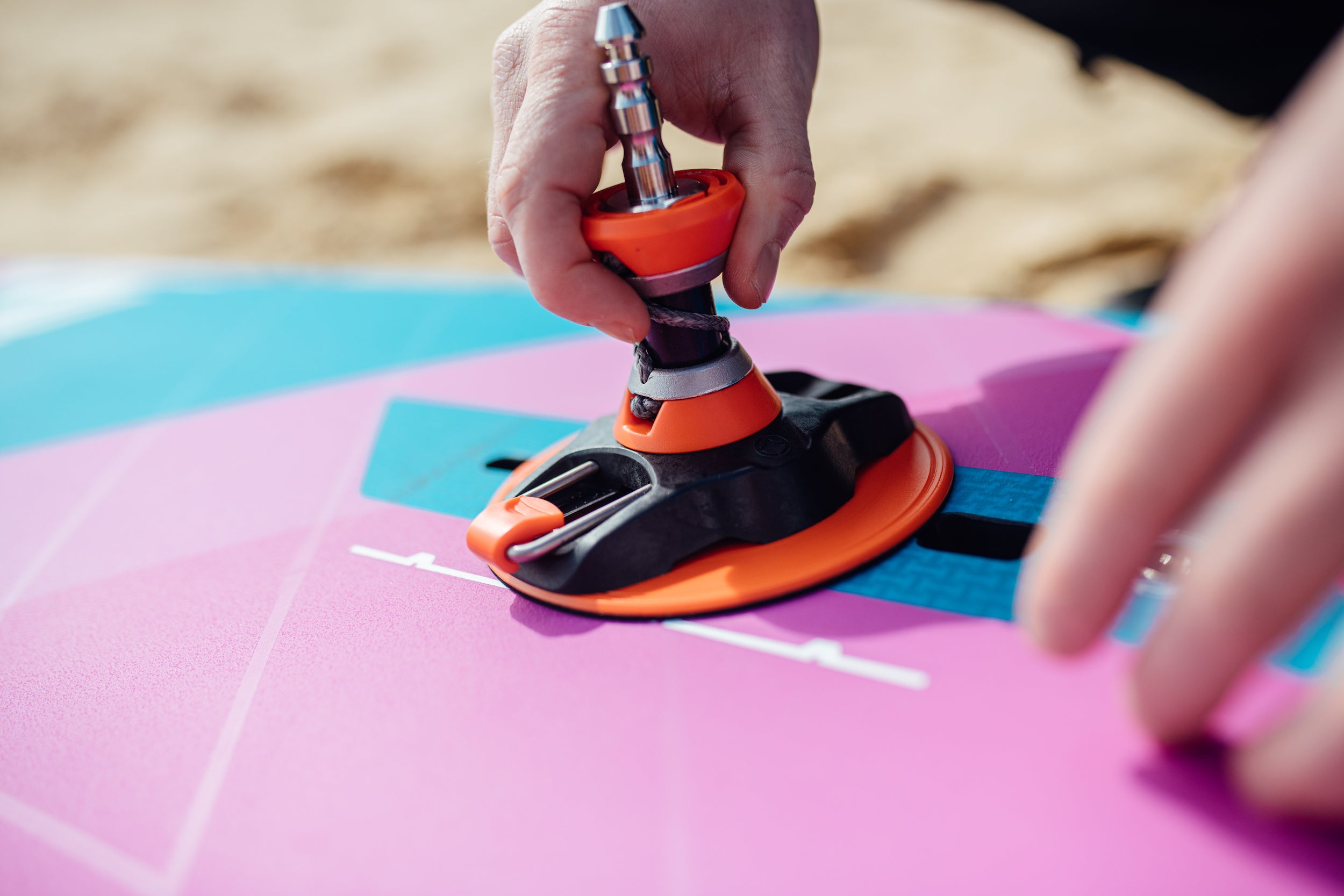 A rider putting his windsurf baseplate on the mast track of a windsurf wave board with a carbon integral construction 