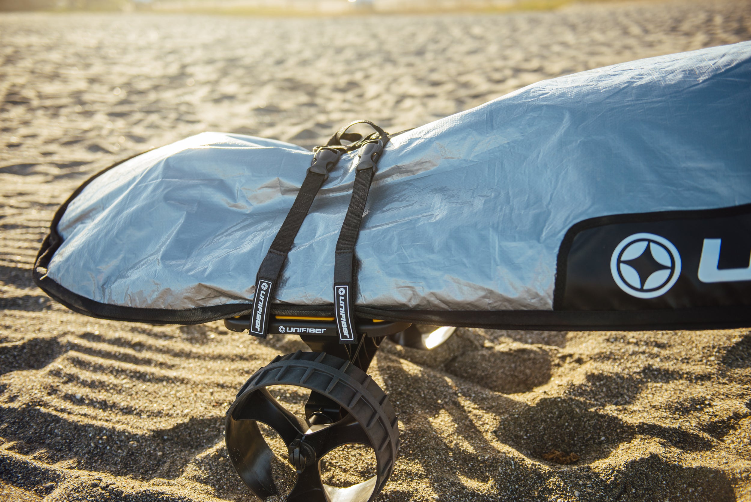 a windsurf board in a grey  bag on a trolley 