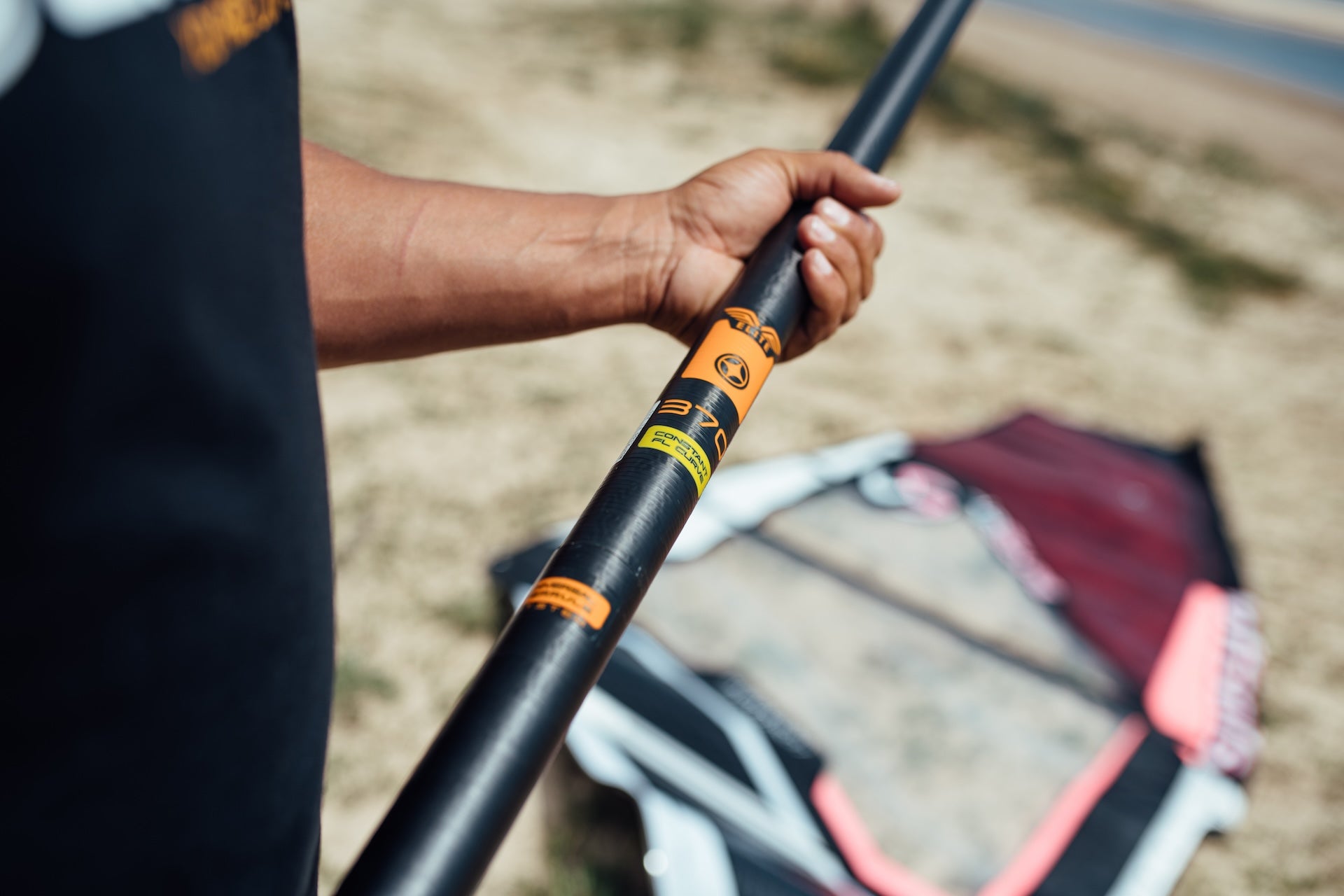 close up image of windsurf rdm mast with orange Unifiber logo. the mast is on the beach and we can see the junction