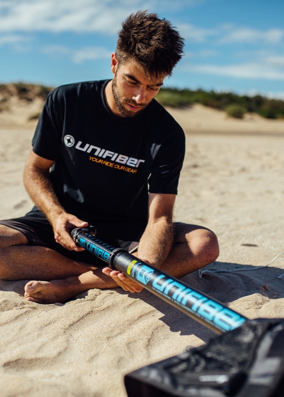 A man rigging a windsurf sail on the beach 
