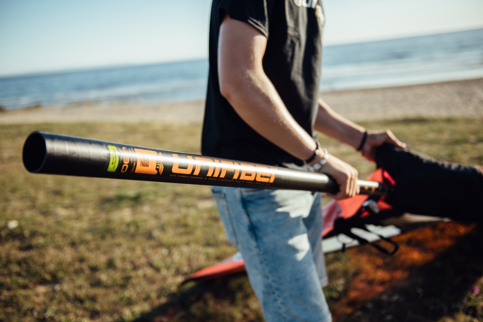 a windsurfer rigging a race sail on the beach