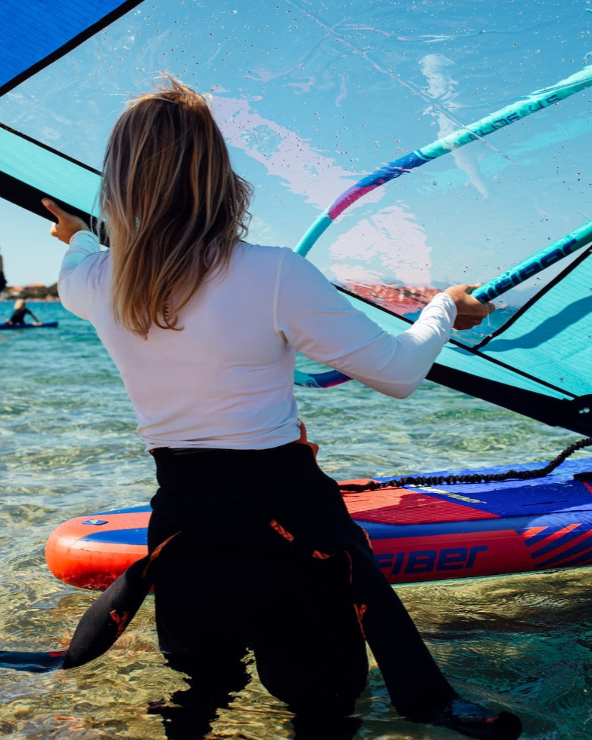 Person windsurfing in clear water with a blue sky